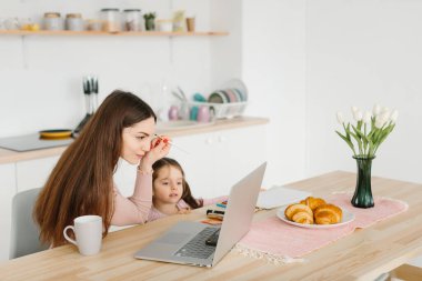 Gülümseyen güzel bir kadın kahvaltıda küçük kızıyla mutfakta otururken barışıyor..