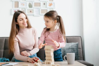 Anne ve kızı oturma odasında masa oyunu oynuyorlar..