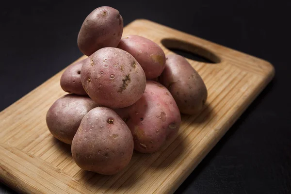 Stapel van aardappelen op houten bureau met zwarte achtergrond — Stockfoto