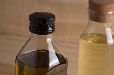 Ahşap arka plan üzerinde cam şişede zeytin ve ayçiçeği yağı
