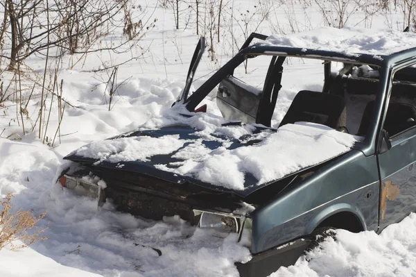 Un coche destruido abandonado en la nieve. Esqueleto del tra innecesario —  Fotos de Stock