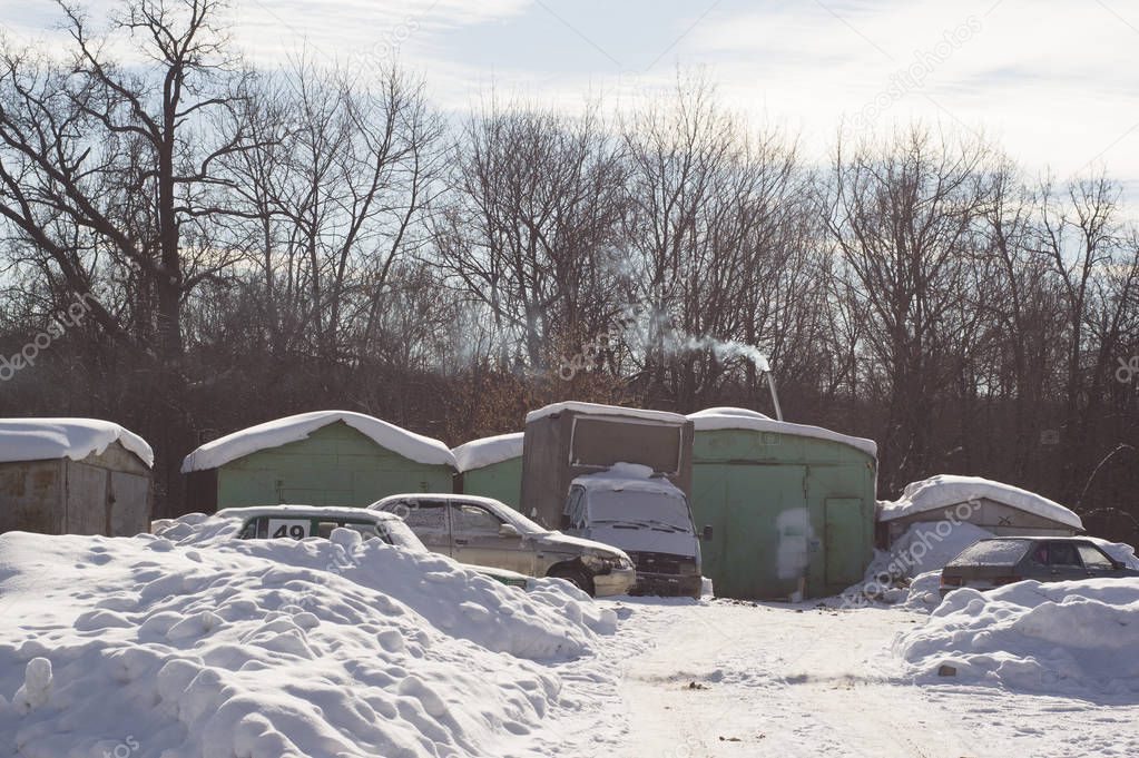 Winter landscape with garages and snow-covered cars. Frosty day 