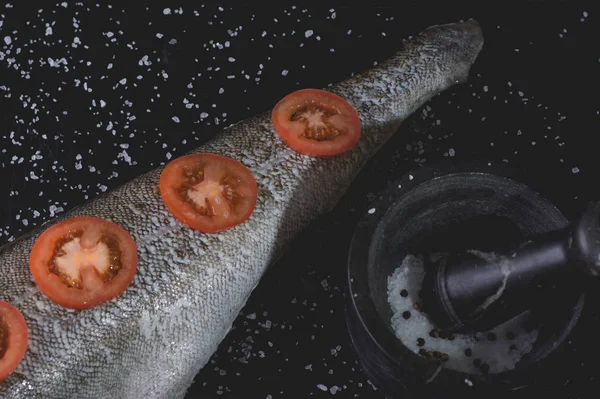 Peixe branco com tomate e argamassa de mármore em um bac de madeira preto — Fotografia de Stock