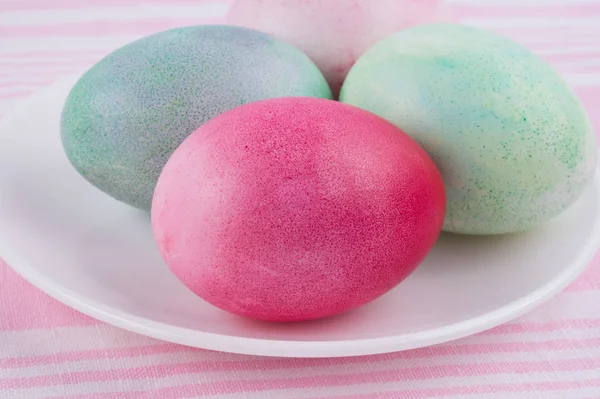 Quatre œufs de Pâques multicolores peints sur une assiette blanche et stri — Photo