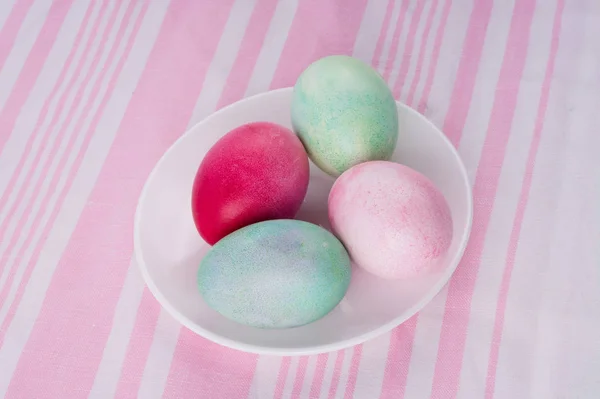 Quatre œufs de Pâques multicolores peints sur une assiette blanche et stri — Photo