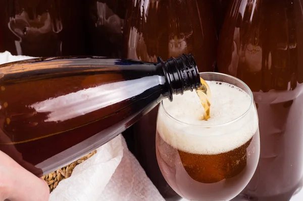 homemade beer from a plastic bottle is poured into a glass again