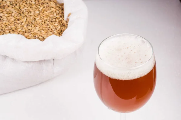 Стакан самодельного ремесленного пива и мешок легкого солода на деревянном солоде — стоковое фото