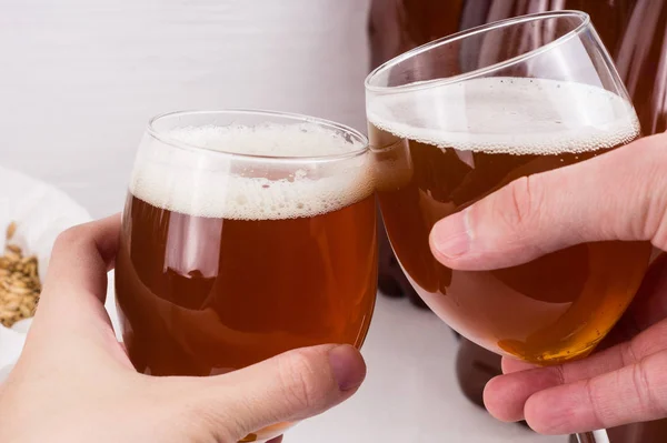 Hausgemachtes Craft Beer im Weinglas in zwei Händen auf weißem Hintergrund — Stockfoto