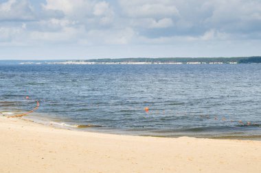 sandy city beach with small waves and buoys
