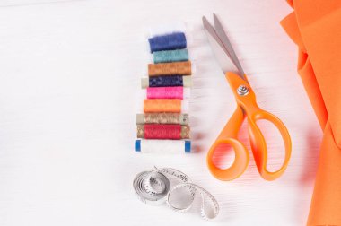 terzi makası, inç, santimetre bant, beyaz ahşap arka planda dikiş ipliği