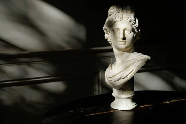 An old Sculpture On a Table, in a Dark Room Or Twilight.