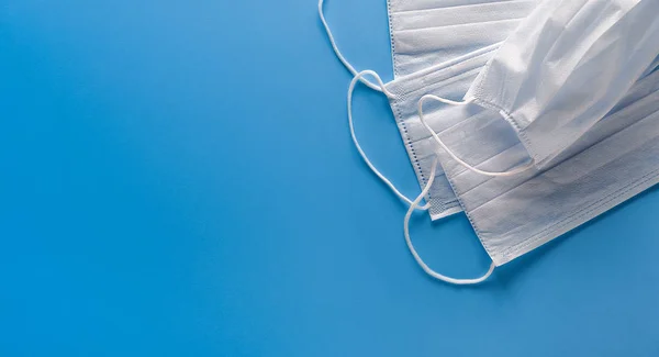 Medical Disposable Face Masks On A Blue Background. Concept Of Air Pollution, Outbreaks Of Pneumonia And Viruses, Epidemics Of Coronaviruses And Prevention Of The Risk Of Biological Pollution. Banner