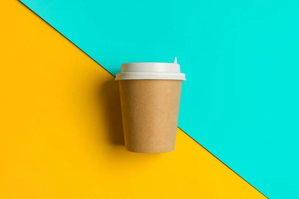 Disposable paper Cup with Lid for Coffee and Tea on a Bright Blue and Yellow Background. Coffee-break.