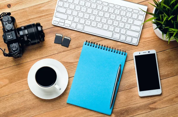 Mobile Phone, Computer Keyboard, Pen And Notepad For Notes, Coffee Mug, Flash Drives And Camera On A Wooden Table. Photographer\'s Items In The Workplace.