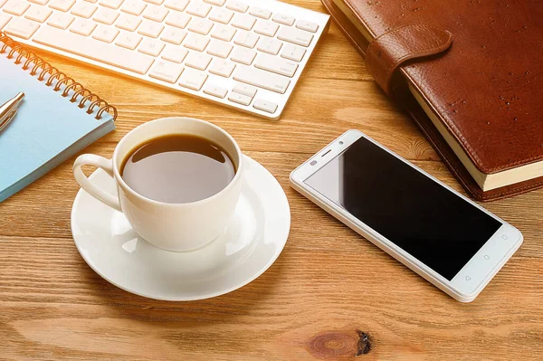 Mobile Phone, Computer Keyboard, Pen And Notepad For Notes, Coffee Mug, On A Wooden Table. Items Of A Businessman Or Manager In The Workplace.