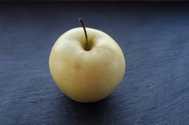 Karanlık bir arka plan üzerinde bir sarı elma