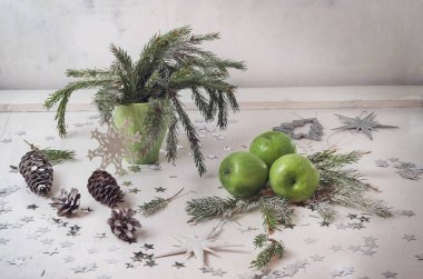 Vazo ile çam dalları, beyaz bir arka plan üzerinde üç yeşil elma