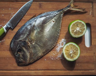 Tütsülenmiş balık kusmuğu, limon ve tuz, mutfak masasının üzerinde duran mutfak bıçağı, yakın mesafeden çekilmiş.