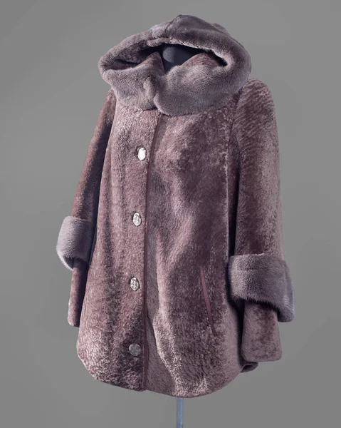 Short flared coat in lilac-powder tones of Mouton and mink trim on the edge of the hood and sleeves, slanting pockets with leather trim. Vertical frame