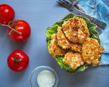 Hafif diyet tavuk pirzolası ve yeşil seramik salata kasesinde marul, cam tencere sosu, kırmızı domates.