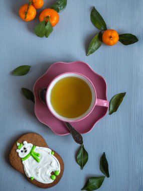 Noel sabahı pembe seramik bir tabakta yeşil çay üzerine zencefilli ekmek ve yapraklı mandalina.