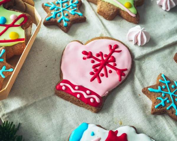 Glazed painted gingerbread in the shape of a mitten in the center of the composition and a scattering of smaller gingerbread