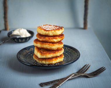 Seramik bir tabakta peynirli kek ve küçük bir sos teknesinde ekşi krema örneği.