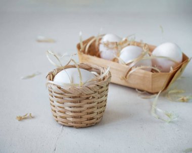 Sepet içindeki yumurtalar yakın mesafeden atılan tahta beyaz bir masanın üzerinde duruyor.