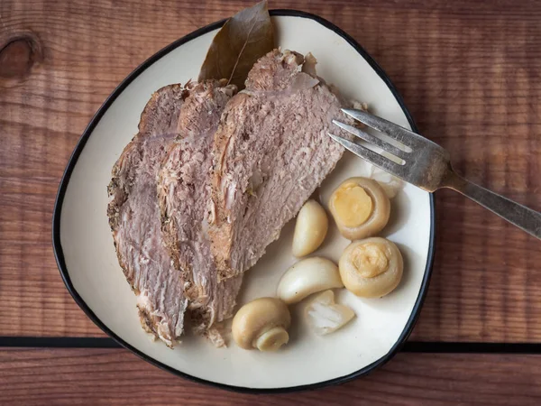 Appetizer with homemade pork ham and pickled mushrooms and garlic on a ceramic plate standing on a wooden tray close-up — 스톡 사진