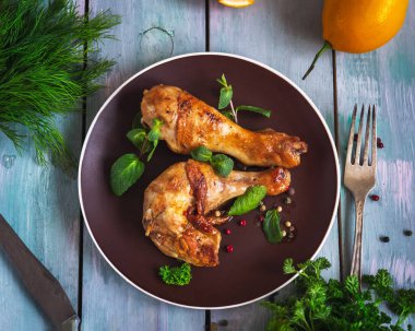 Yuvarlak seramik tabakta otlu tavuk budu, üst manzara.