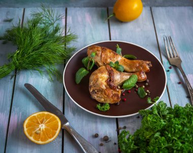 Fırında tavuk budu ve limon suyuyla marine edilmiş seramik tabakta kahvaltı. Masada yarım limon.
