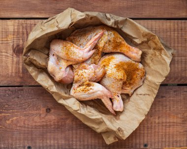 Kağıt üzerinde tavuk bacağı ve kanatları bölümlere ayrılmış, yemek pişirmeye hazır, yakın plan.