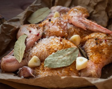 Baharatlarla süslenmiş porsiyonlu tavuk eti parçaları ahşap bir masanın üzerinde uzanıyor.