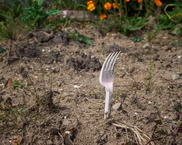 Call to protect the environment , empty land with a plastic fork, in the background blooming marigolds, close- up