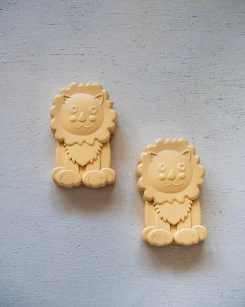Baby curly soap in the form of a cheerful lion on a white wooden table, top view
