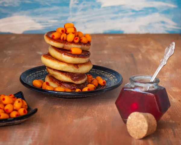 Desayuno ligero con panqueques, bayas congeladas de espino cerval de mar y jarabe de fruta, de pie sobre una mesa de madera — Foto de Stock
