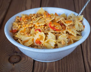 Tavuklu ve biberli makarna, ahşap bir tepside, ahşap bir tepside, yakın planda bir kaşıkla derin bir tabakta yaşardı.