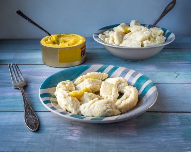 İki seramik tabakta tembel köfteler ve kırsal bir mutfağın ahşap masasında erimiş tereyağı.