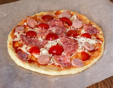 Ev yapımı pizza sosis ve domatesle pişirmeye hazırlandı.