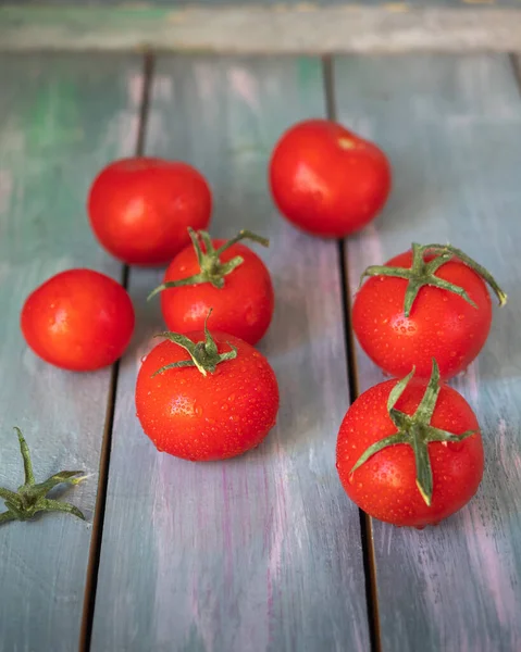 Red ripe tomatoes with leaves on a wooden white table at close range