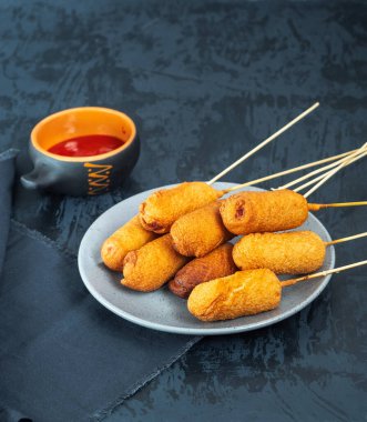 Testte sosis var. Şiş üstünde kızarmış sosisle hızlı bir kahvaltı ve siyah arka planda rendelenmiş domatesli bir fincan.