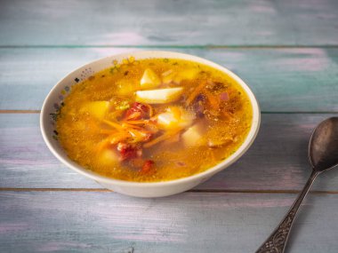 Ev yapımı taze pişmiş çorba, derin bir tabakta füme domuz pirzolası ve ahşap bir turkuaz masa üzerinde yemek kaşığı.