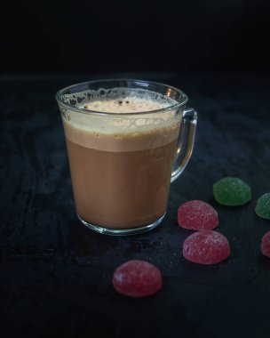 Cam bardakta köpüklü kahve ve koyu arka planda marmelat, tatlı öğle yemeği.