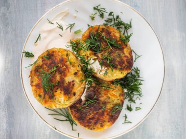 Güzel bir atıştırmalık. Beyaz bir tabakta kesilmiş taze otlarla süslenmiş sebze pirzolaları, üst görünüm.