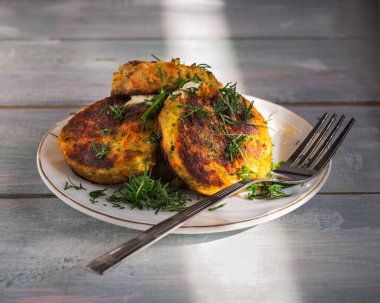 Yakın plan çatallı hafif bir tabakta taze otlar serpiştirilmiş sebze pirzolası.