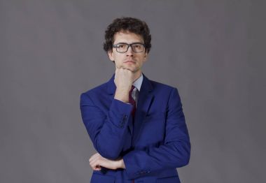 Mavi ceket ve gözlük ile ayakta düşünceli kıvırcık çocuk