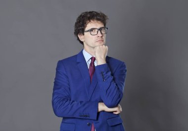 Genç adam kıvırcık saçlı ve ayakta ve yumruğunu tutmak gözlük sakal