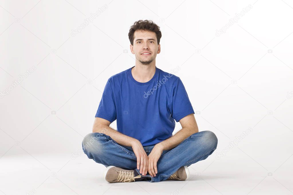 Nice boy in shirt and jeans sitting with crossing legs