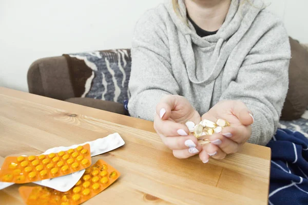 Woman taking medicine capsules at home