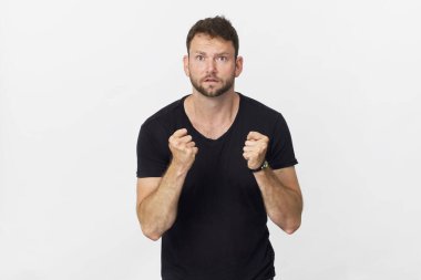 Parmaklarını çapraz yapıp beyaz arka planda gülümseyen genç bir adam.